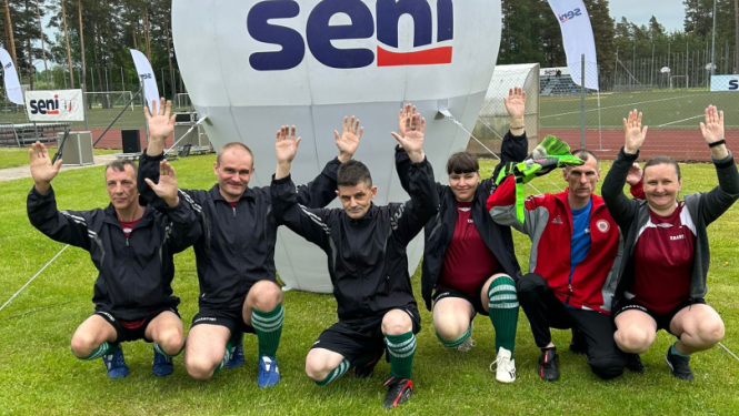 Cilvēku grupa pie Seni Cup banera