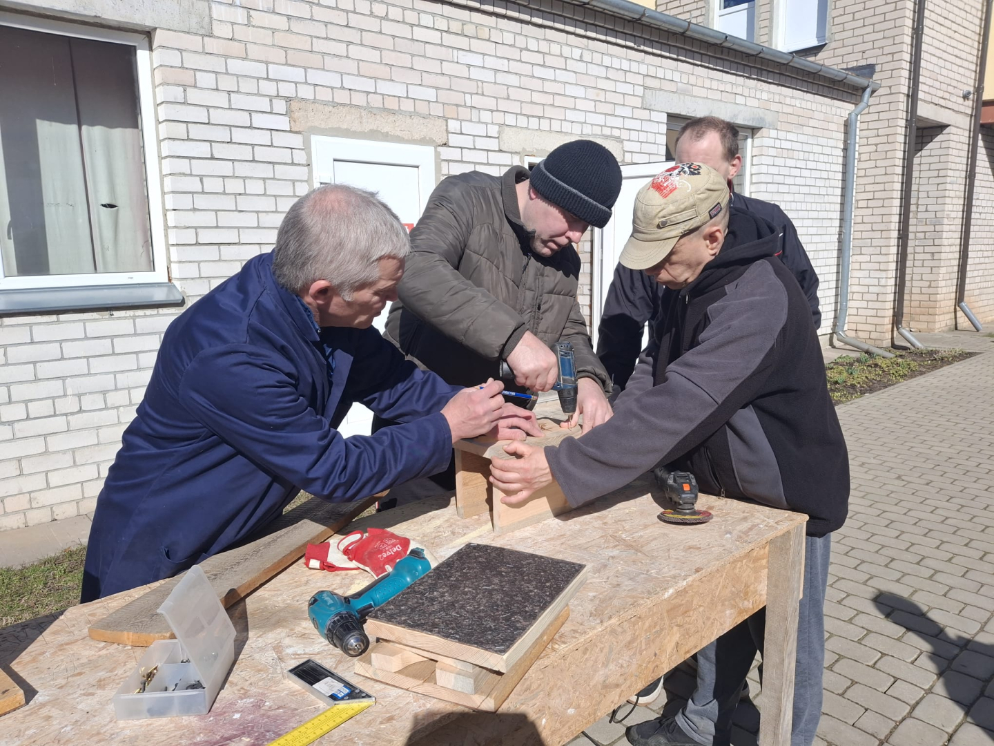 Cilvēki ārā gatavo putnu būrīšus