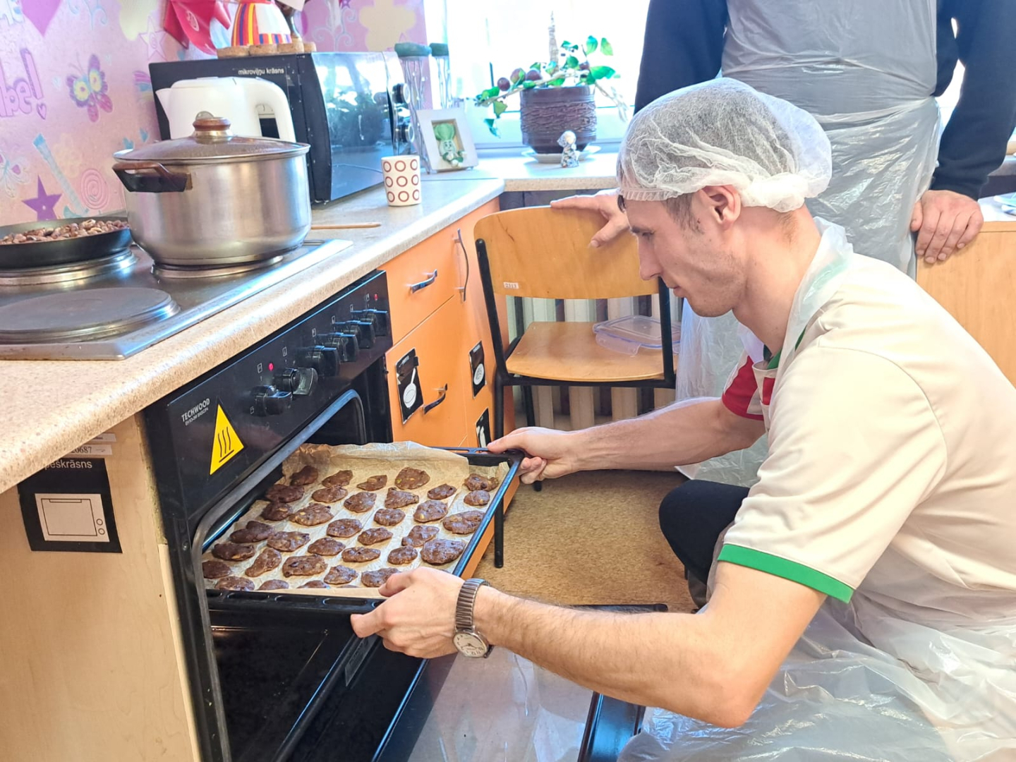 Vīrietis liek pannu cepeškrāsnī