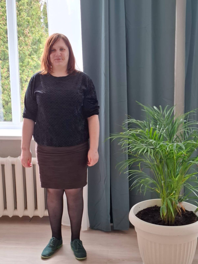 Svieviete melnā kleitā stāv pie puķupoda