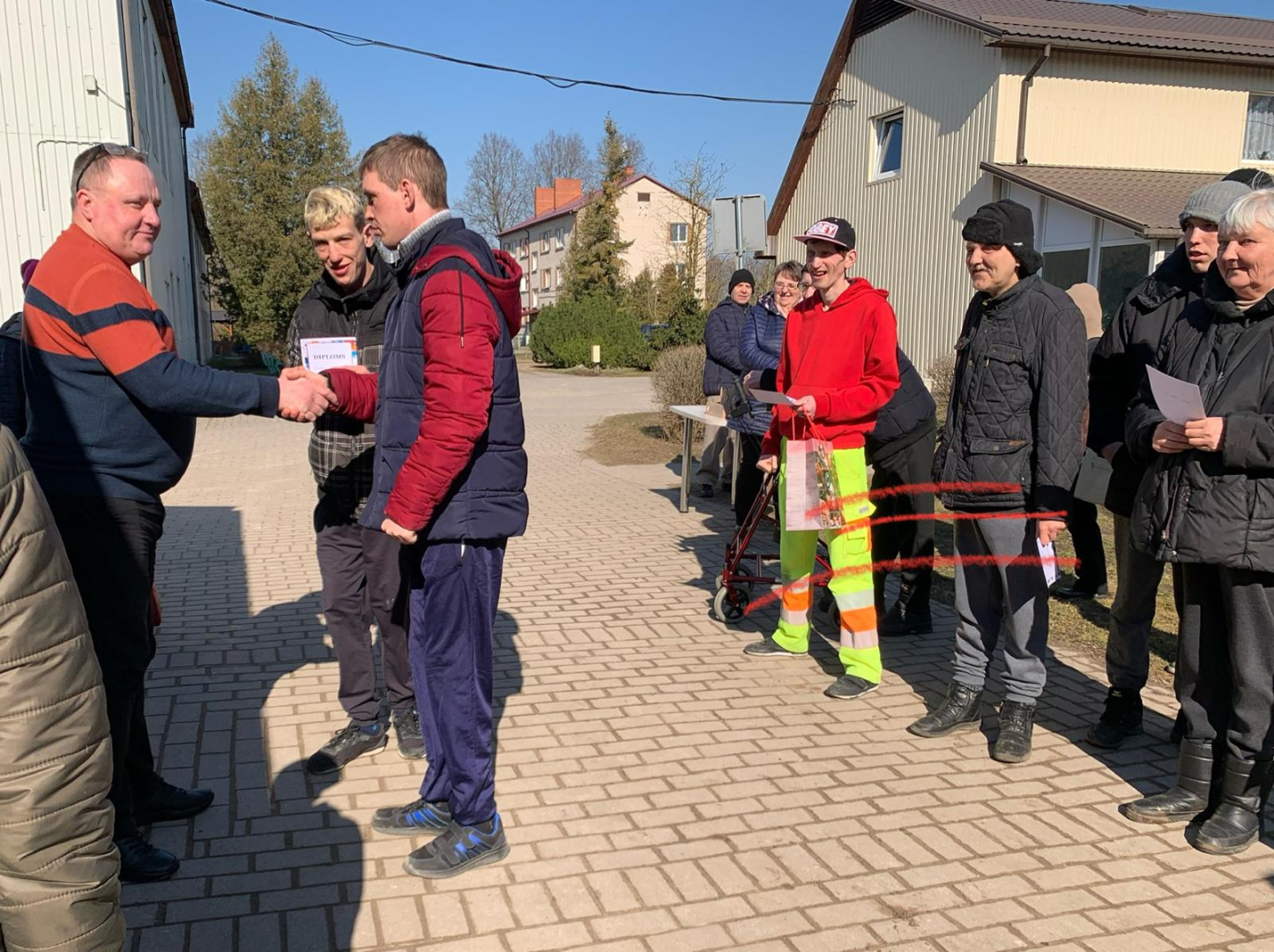 Cīlvēku grupa laukā uz bruģa