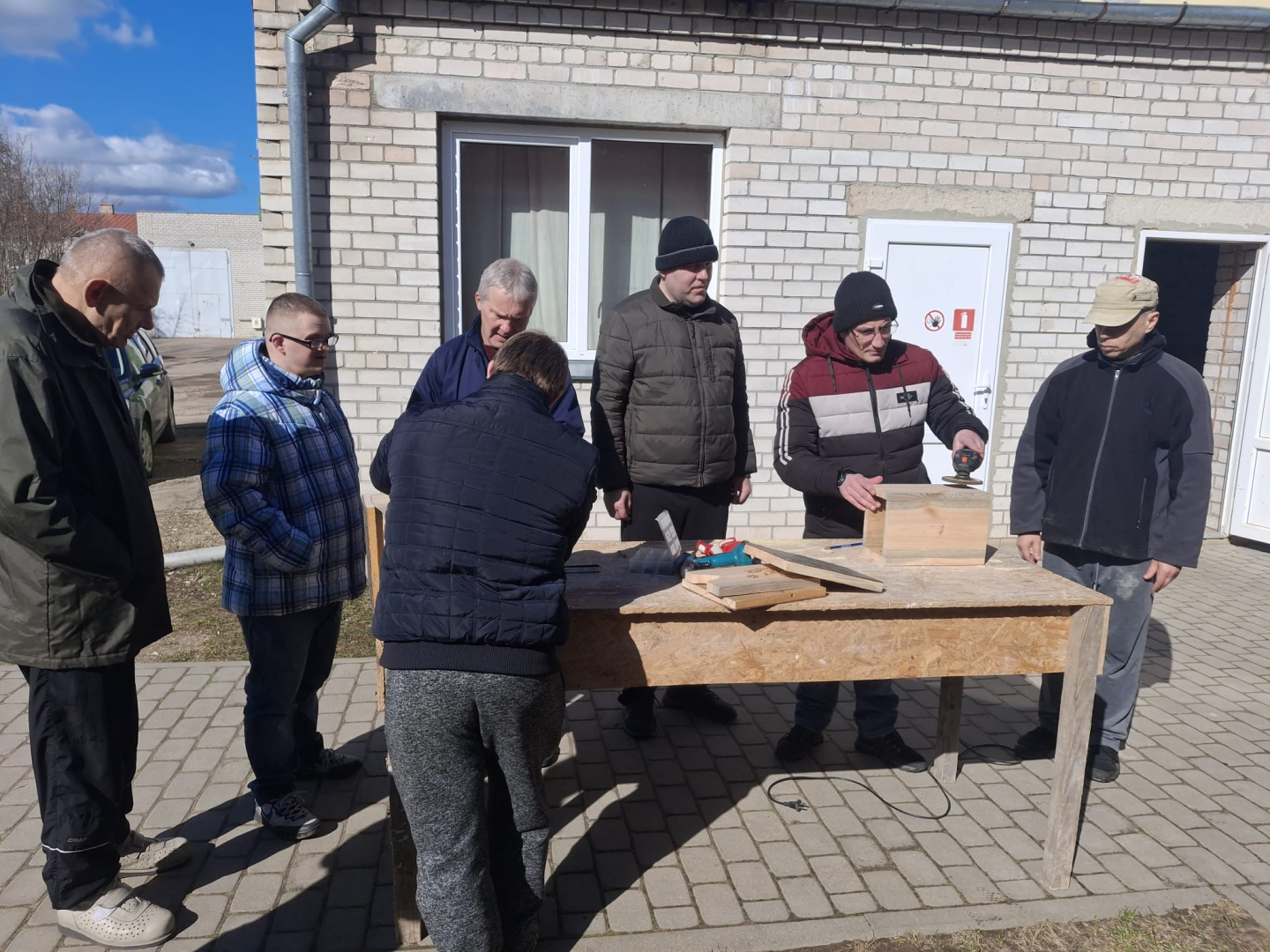 Cilvēki ārā gatavo putnu būrīšus
