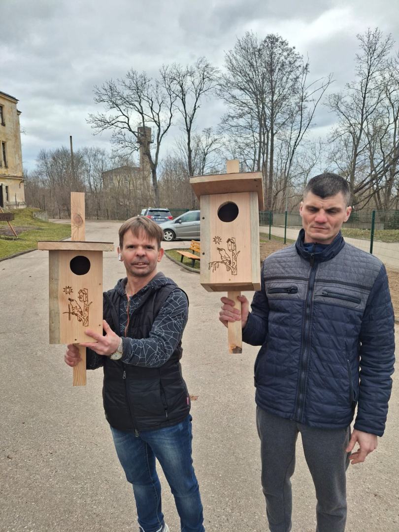 Vīrieši tur rokās putnu būri