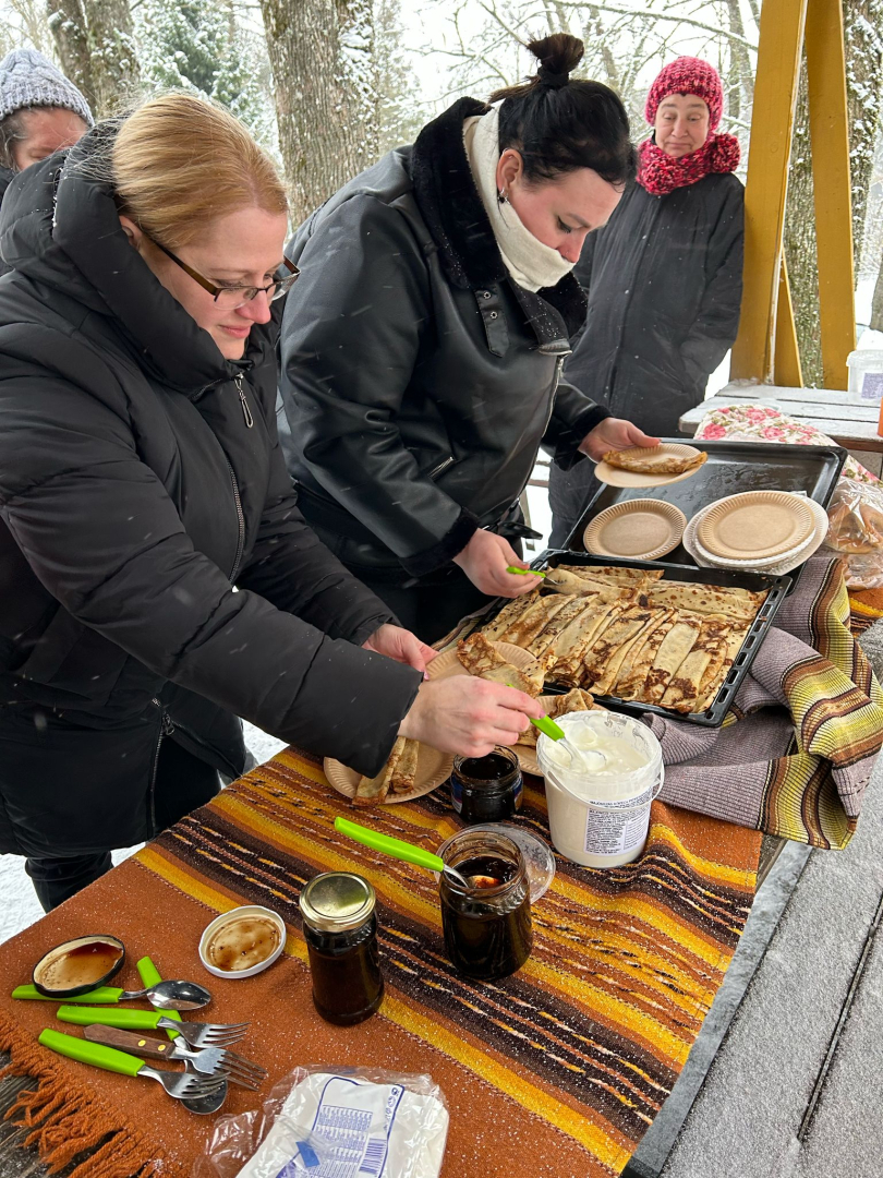 Cilvēki ārā pie galda mielojas