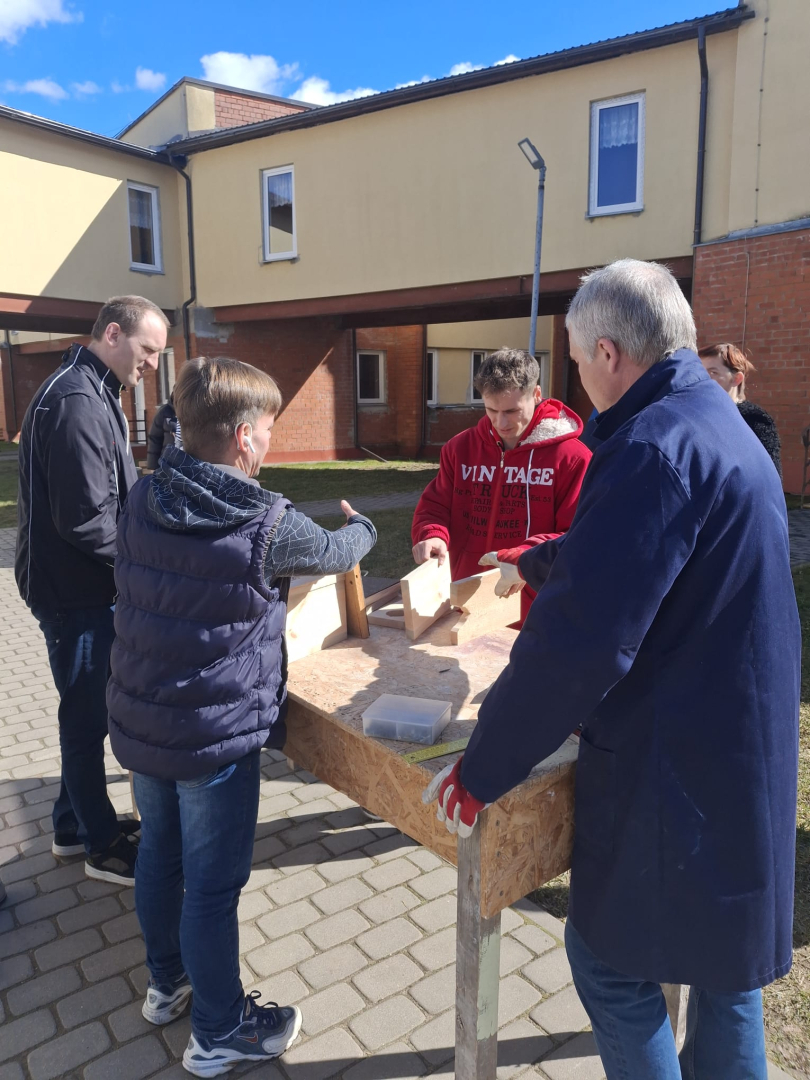 Cilvēki ārā gatavo putnu būrīšus