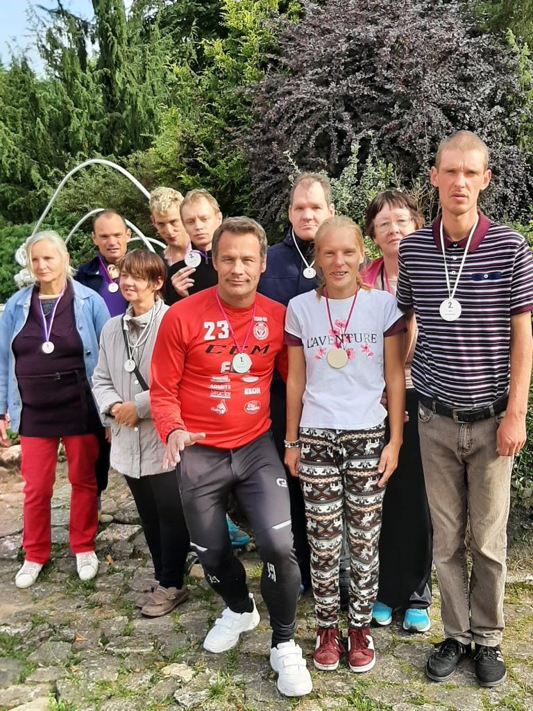 Cilvēkiu grupa s'tav fotogrāfijai, fonā augi