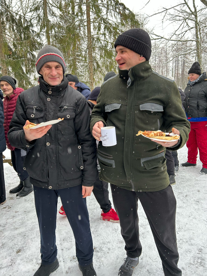 Vīrieši ziemas dienā ārā ar ēdienu rokās
