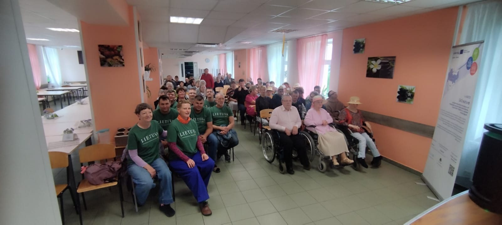 Cilvēku grupa svinīgā pasākumā sēž zālē