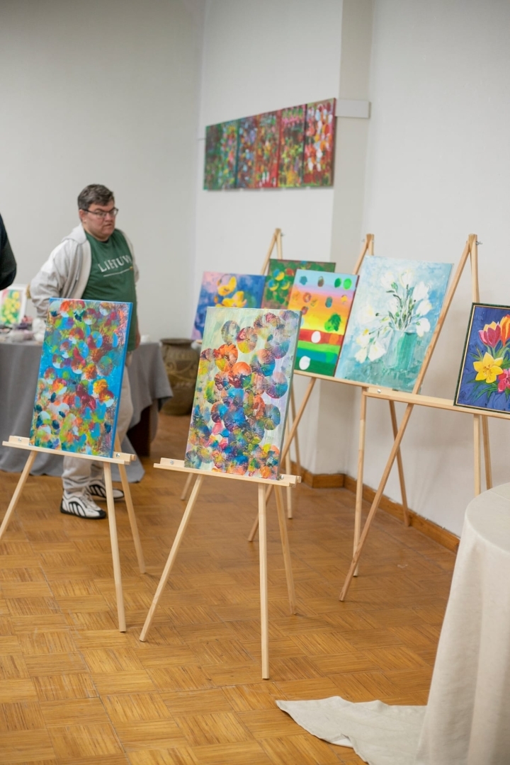 Sieviete aplūko gleznas uz statīviem
