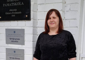 Sieviete stāv pie ēkas ieejas