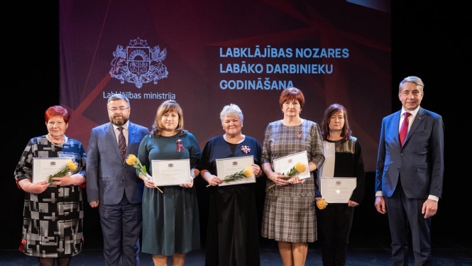 Cilvēki uz skatuves svinīgā pasākumā