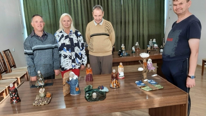 Cilvēki pie galda ar māla sklulptūriņām