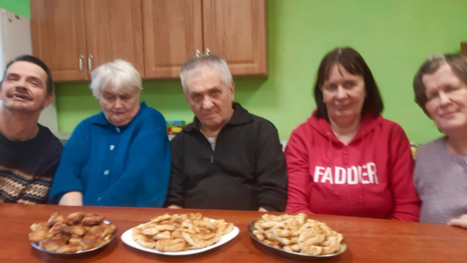 Cilvēku grupa pie galda, uz galda pīrāgu šķivji