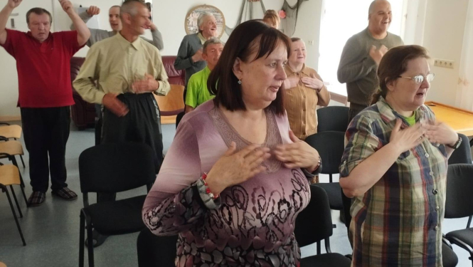 Cilvēki stāv telpā ar paceltām rokām