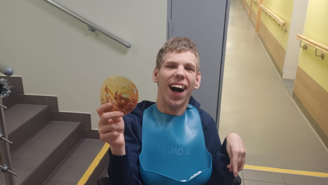 Vīrietis ratiņekrēslā ar ziemasvētku egles rotājumu