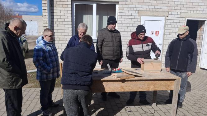 Cilvēki ārā gatavo putnu būrīšus
