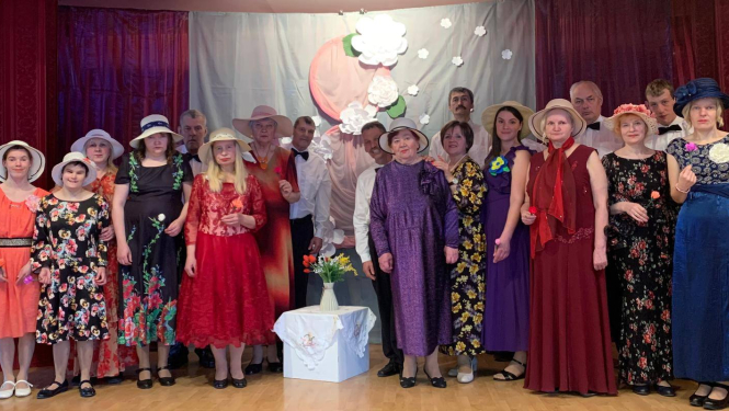 Sieviešu grupa uz skatuves svētku kleitās