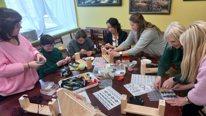 Cilvēki pie galda veido rokdarbus