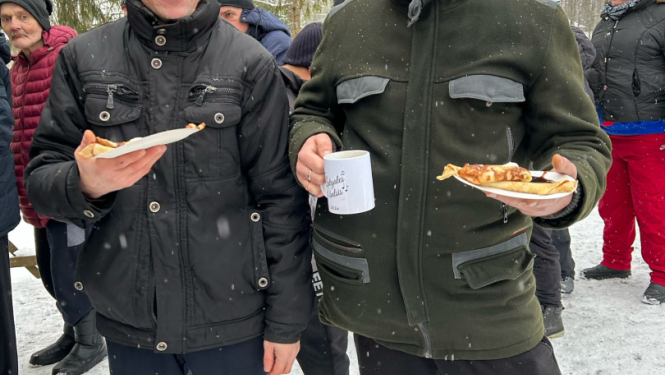 Vīrieši ziemas dienā ārā ar ēdienu rokās