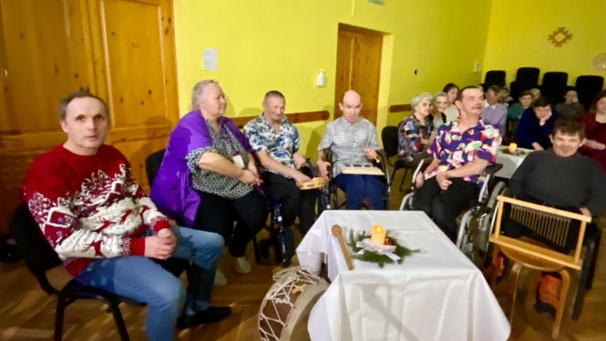 Ziemassvētku pasākumā cilvēki sēž pie galda