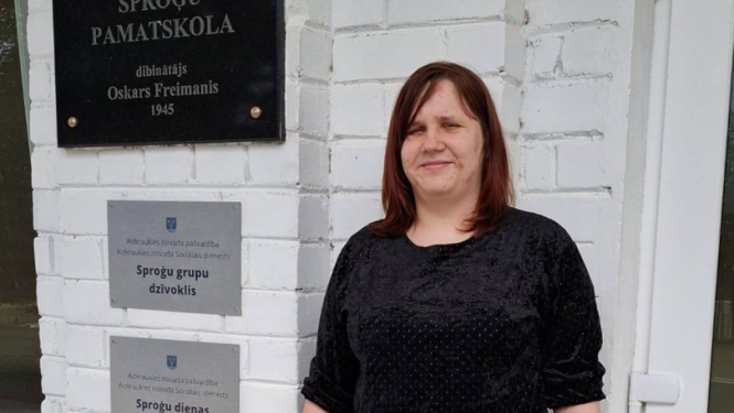 Sieviete stāv pie ēkas ieejas