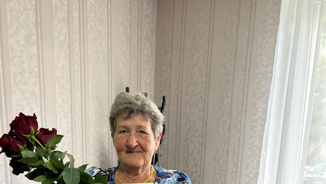 Sieviete tura rokā godarakstu un ziedus