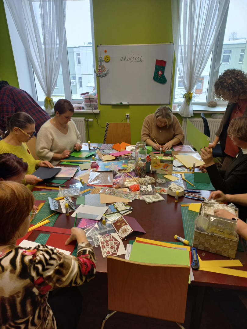 Cilvēki pie galda veido rokdarbus