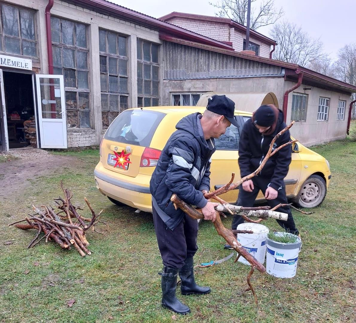 Vīrieši laukā darbojas ar koku zariem