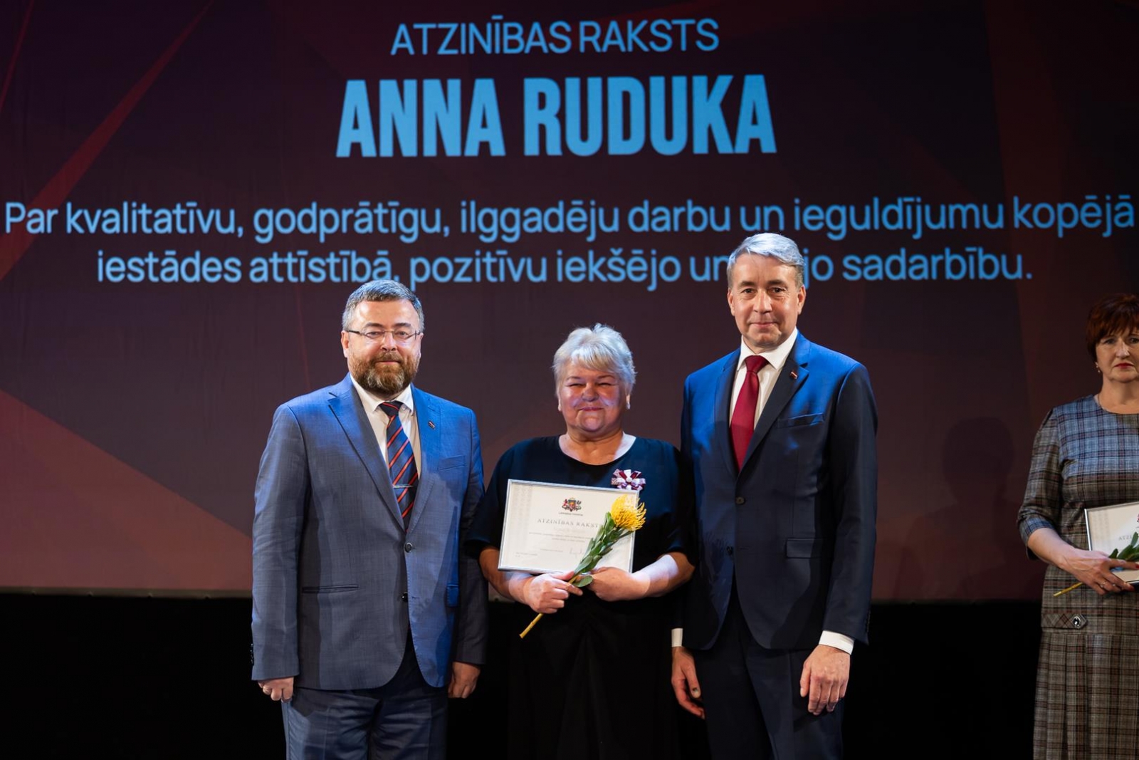 Cilvēki uz skatuves svinīgā pasākumā