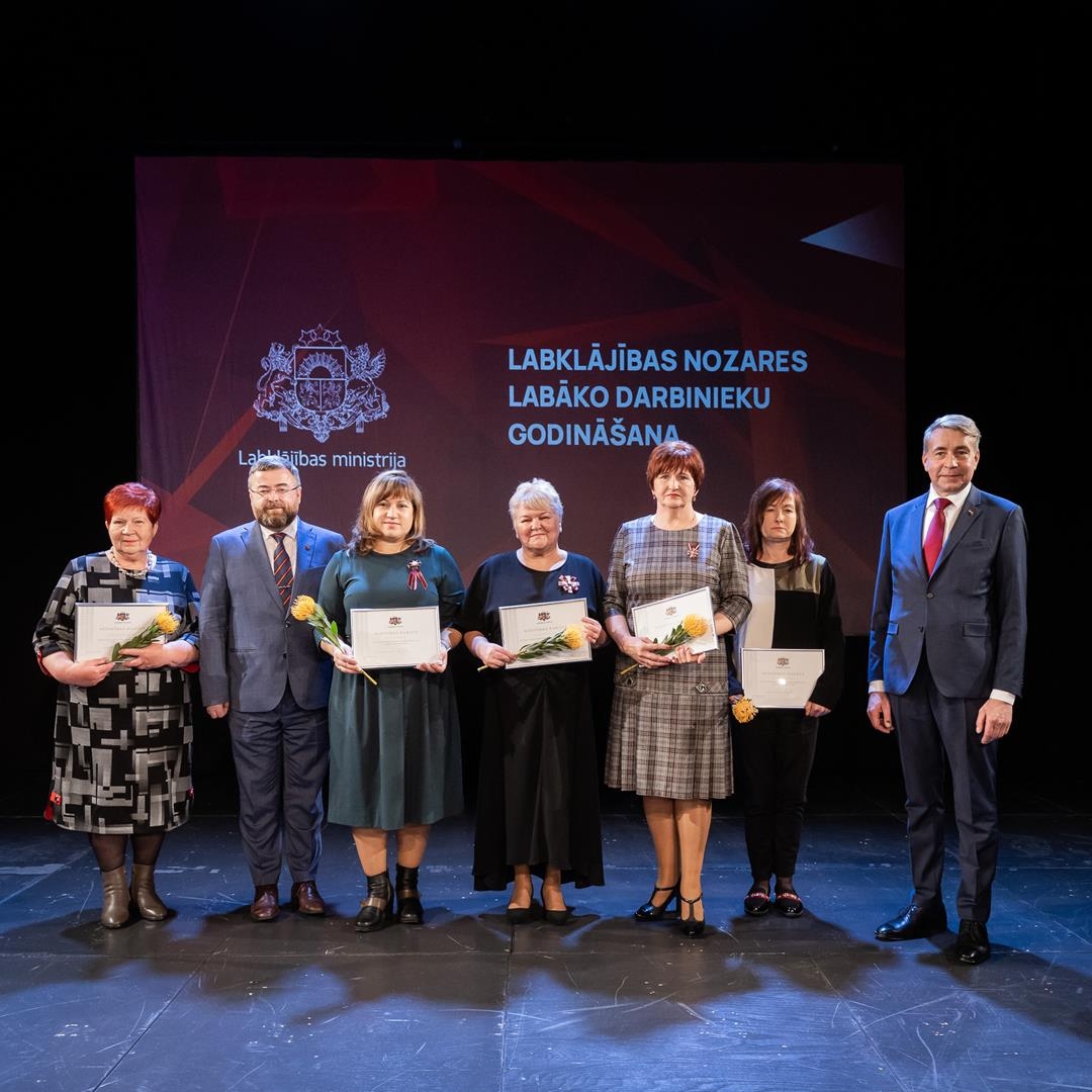 Cilvēki uz skatuves svinīgā pasākumā