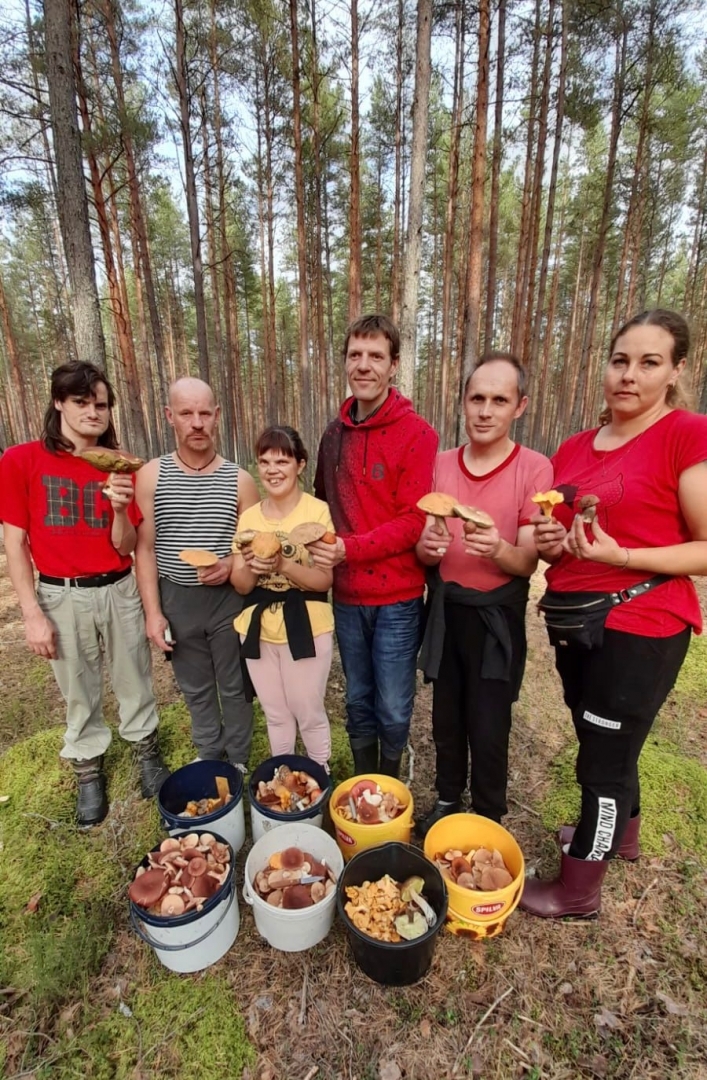 Stāv cilvēku grupa, uz zemes sēņu grozi