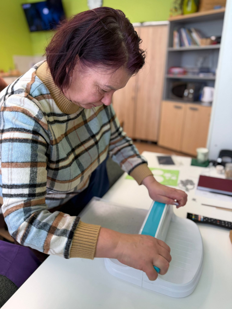 Cilvēki pie galda veido rokdarbus