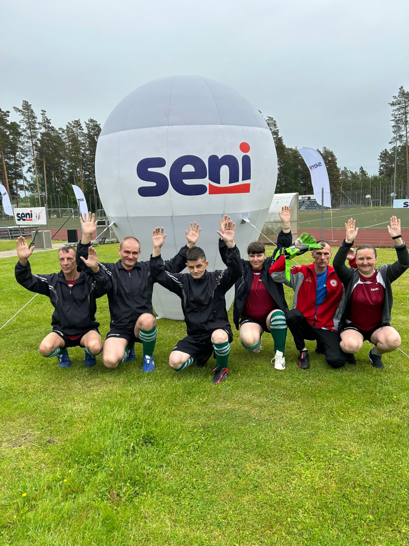 Cilvēku grupa pie Seni Cup banera