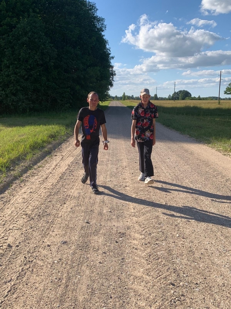 2 cilvēki iet pa grants ceļu