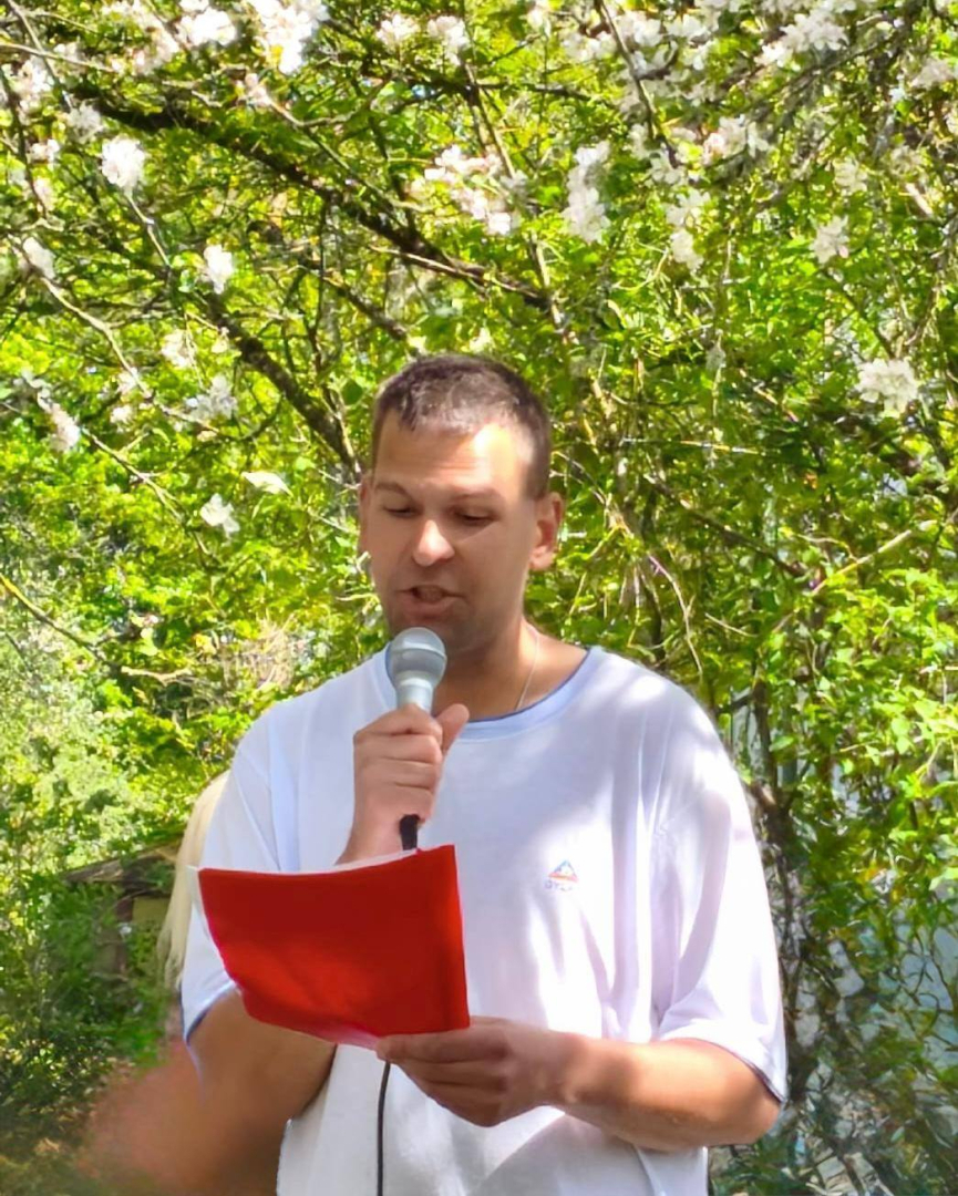 Vīrieis no lapas lasa, stāv pie ziedošas ābeles