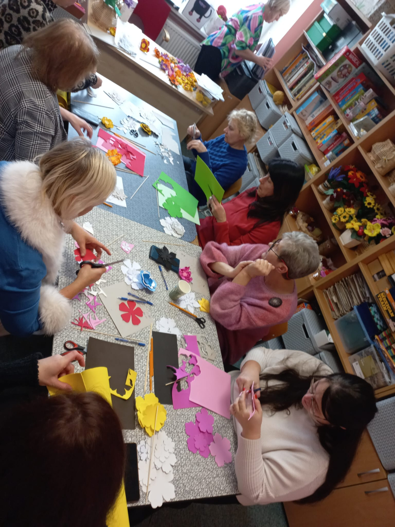 Cilvēki pie galda veido rokdarbus