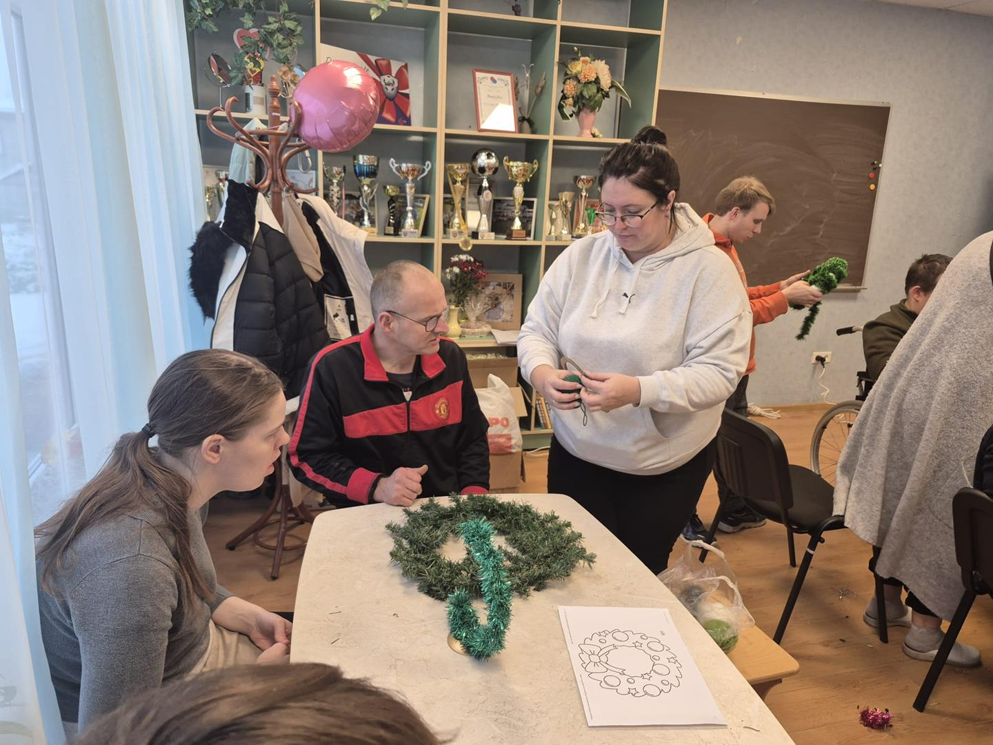 Cilvēki pie galda gatavo ziemassvētku rotājumus