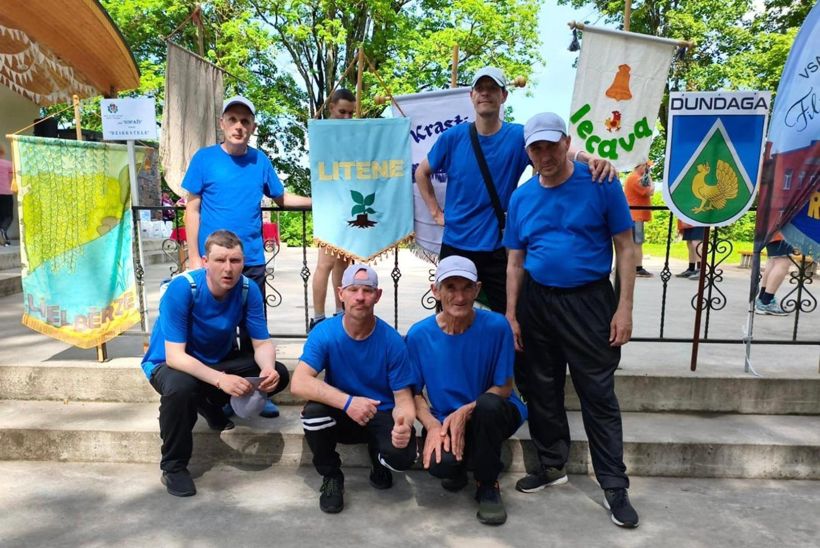 Dalībnieku komanda pie komandu karogiem