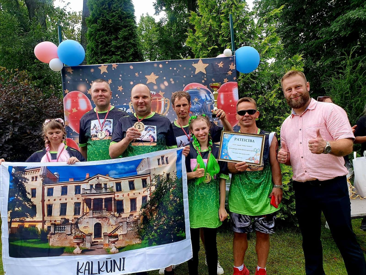 Sportistu komanda ar plakātu un filiāles vadītāju