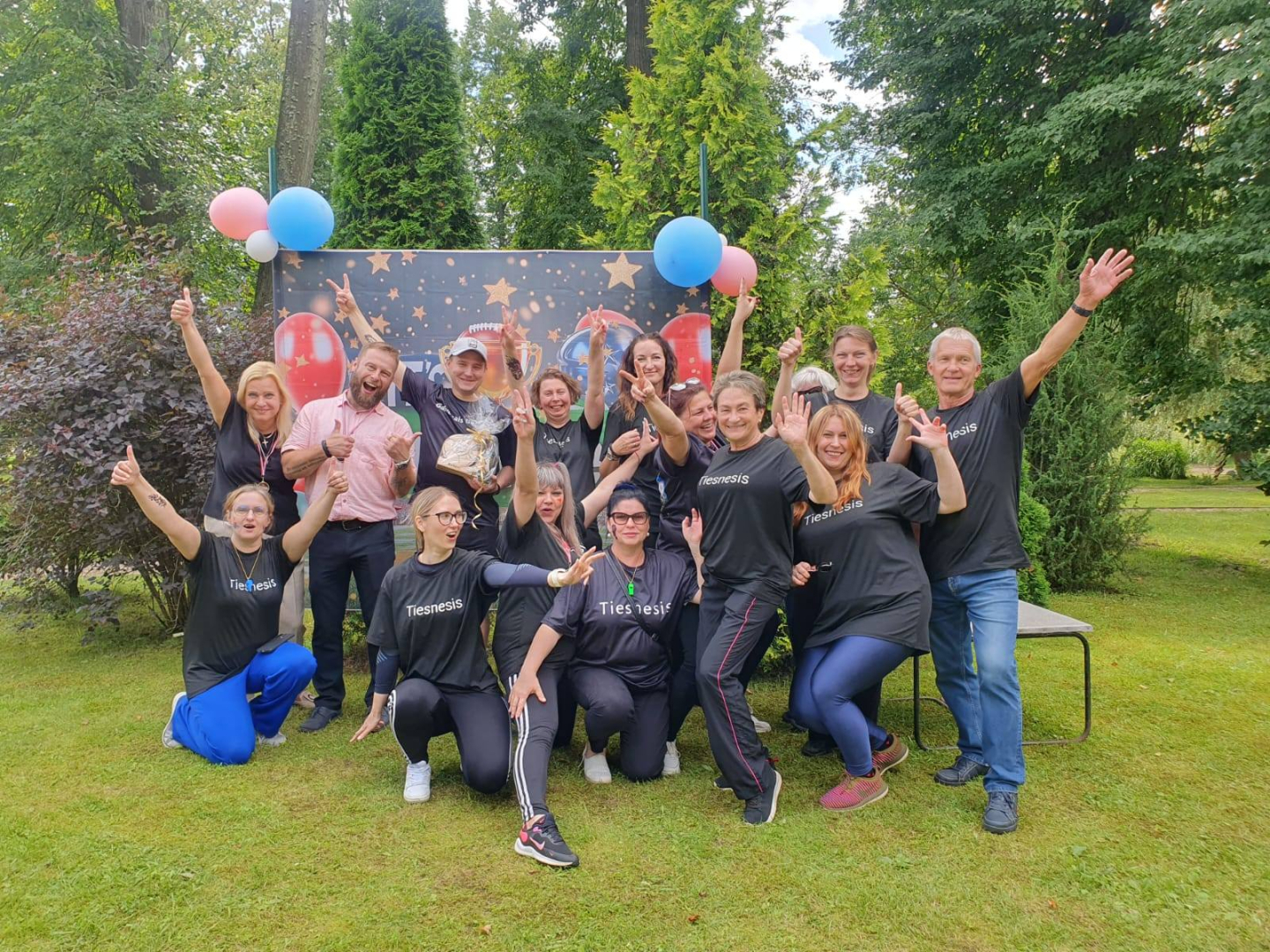 Sportistu komanda pozē pie plakāta