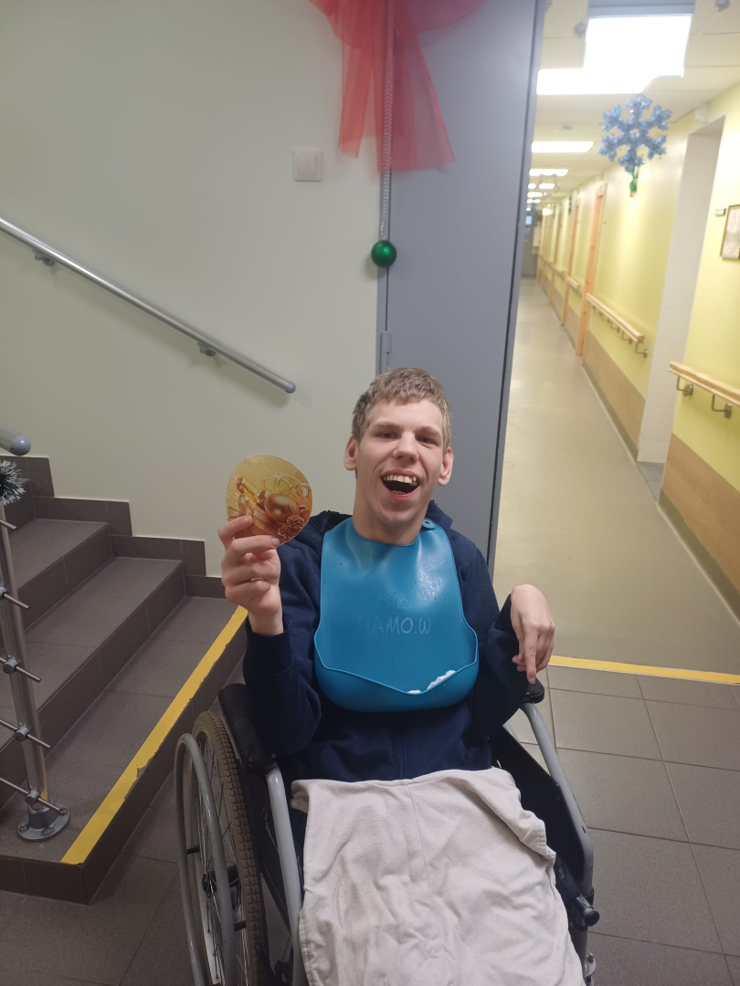 Vīrietis ratiņekrēslā ar ziemasvētku egles rotājumu