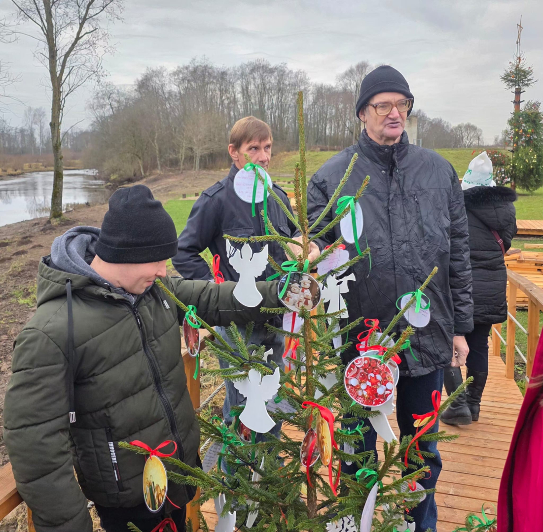 Cilvēku grupa pie ziemassvētku egles