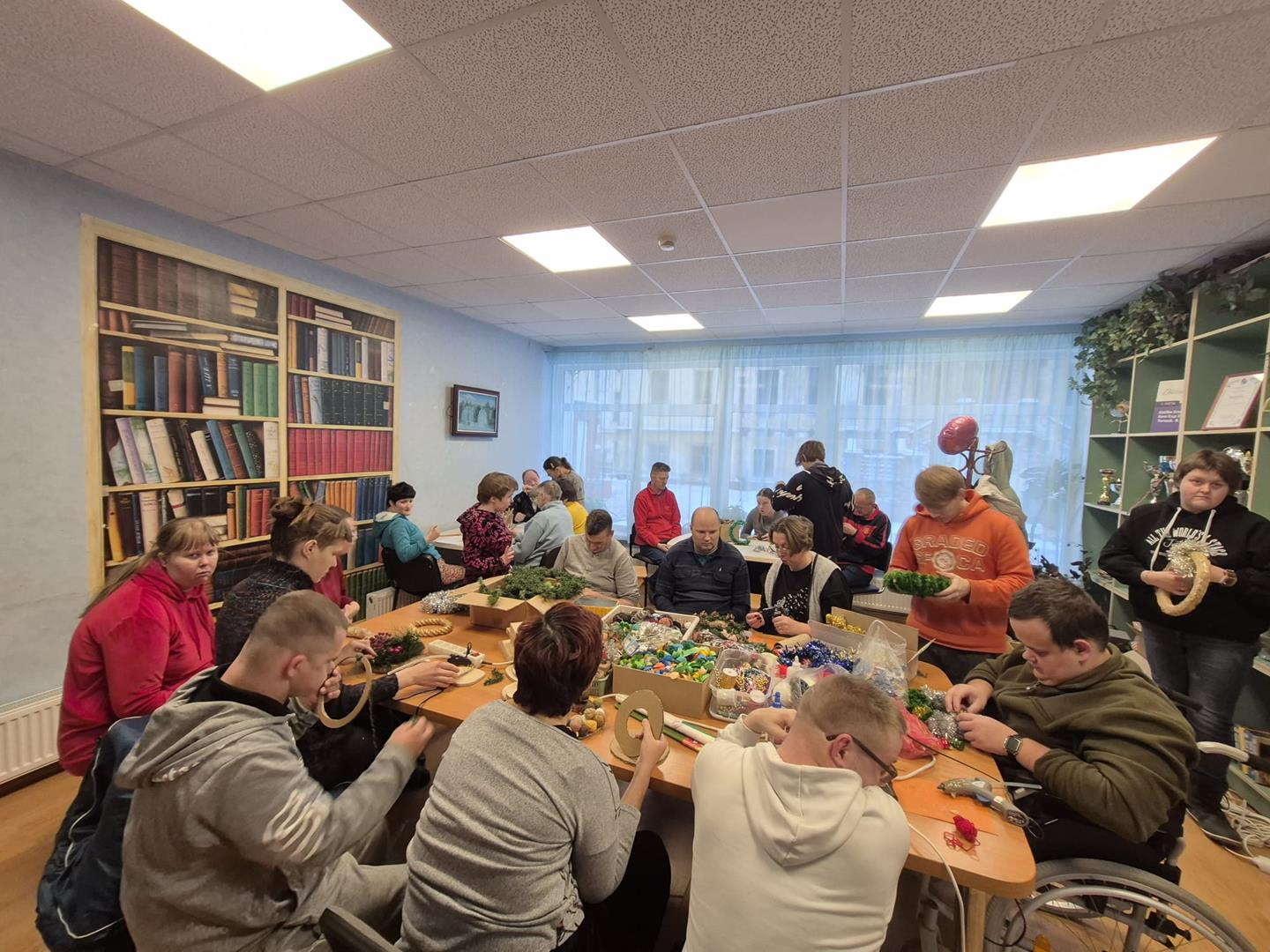 Cilvēki pie galda gatavo ziemassvētku rotājumus