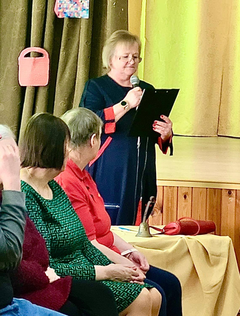 Sieviete runā mikrofonā zāles priekšā