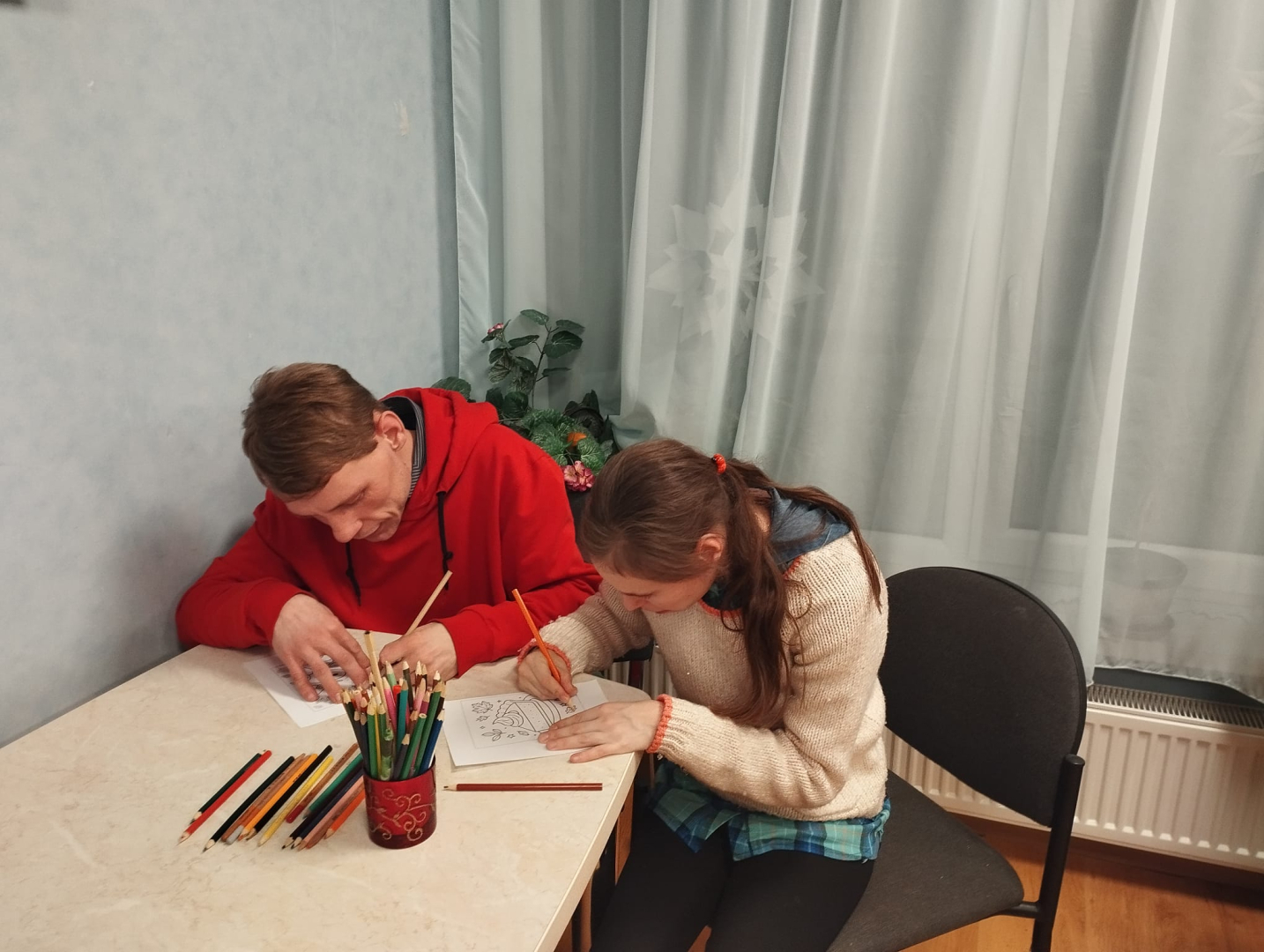 Cilvēki pie galda zīmē