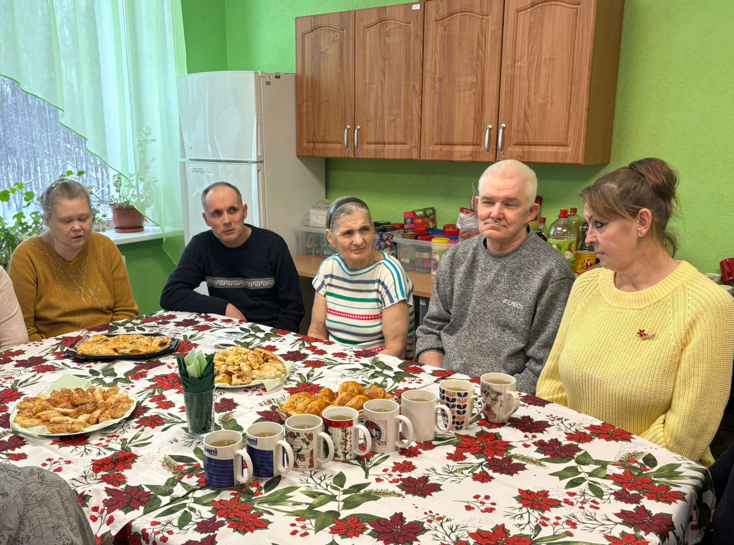 Cilvēki pie galda, uz galda pīrāgi