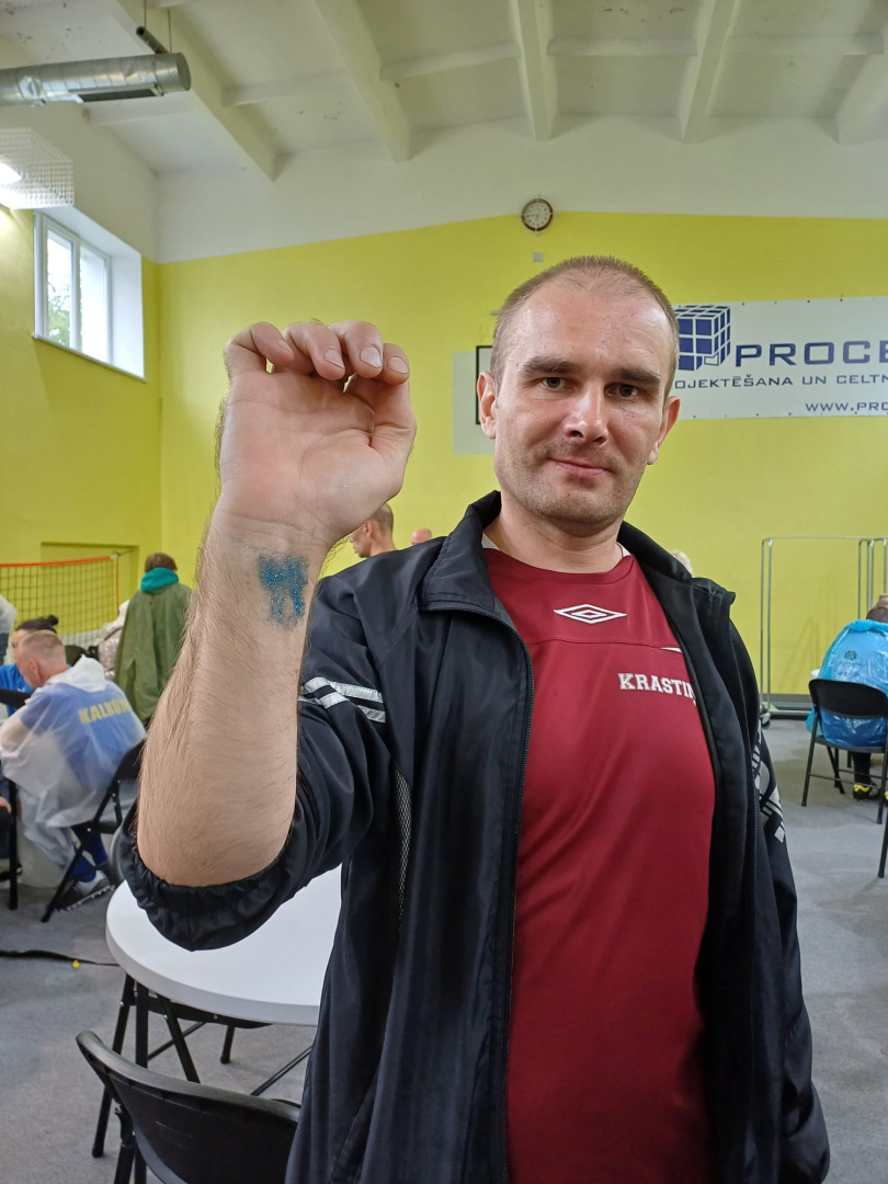 Vīrietis sporta zālē ar paceltu roku