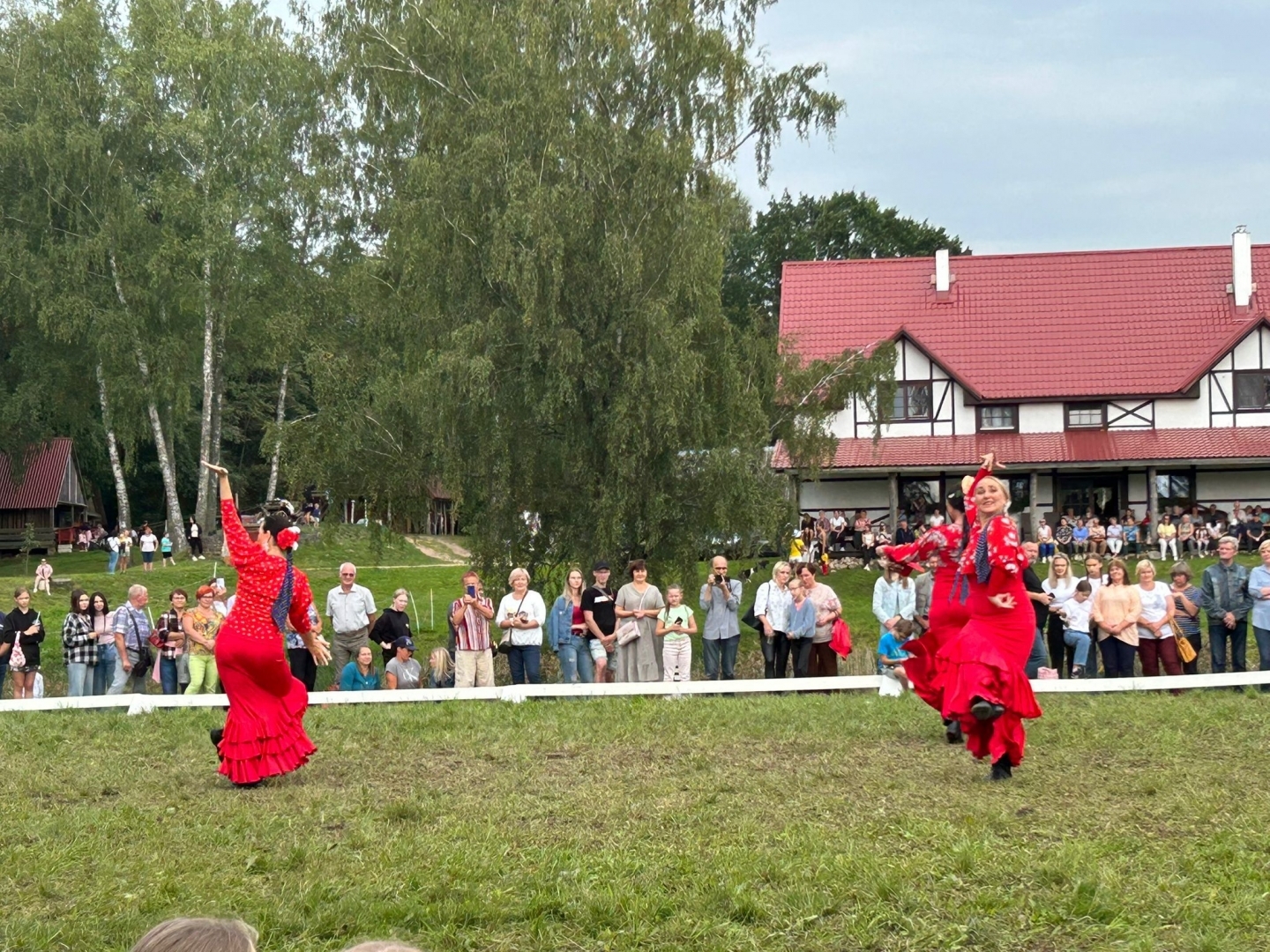 Sievietes sarkanās kleitās dejo