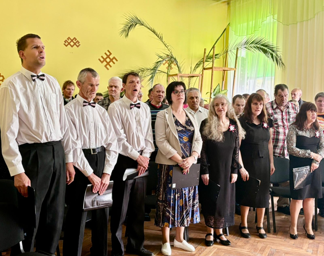 Cilvēku grupa zālē, svētku drēbēs