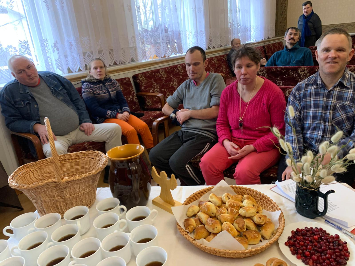 Galds ar pīrākiem un tēju, pie galda cilvēki